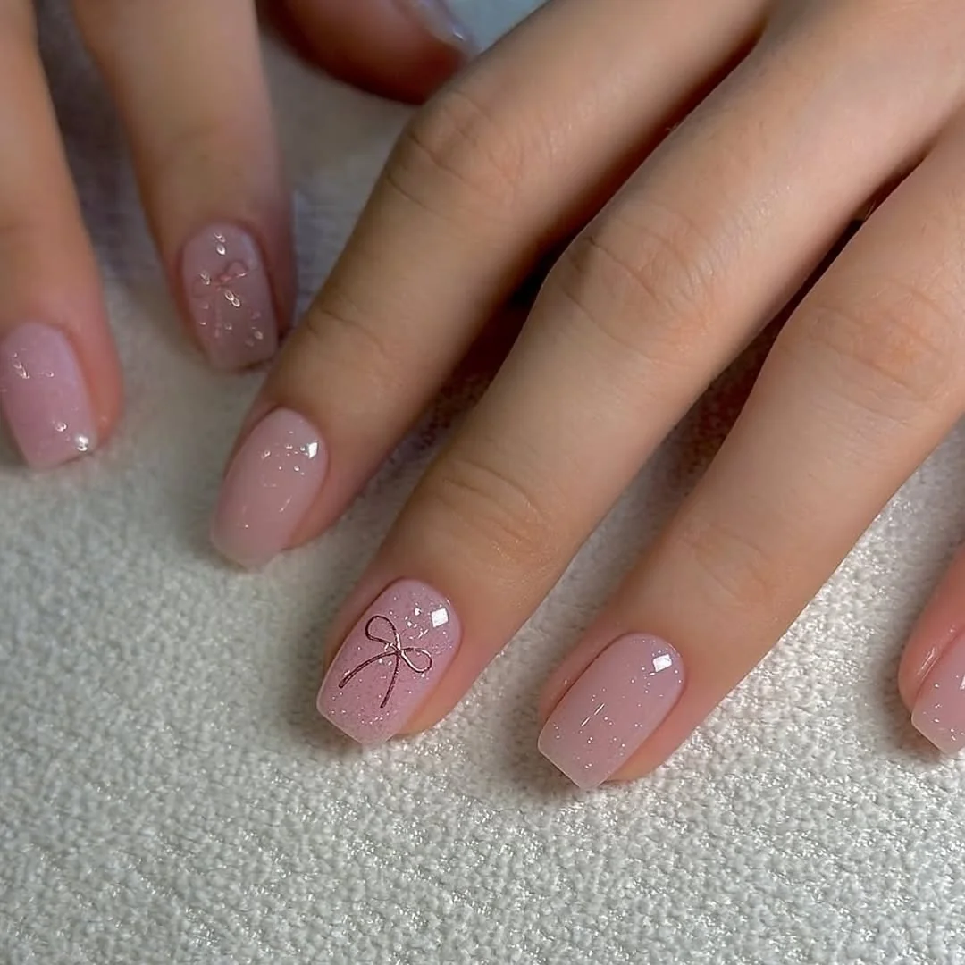 Sheer pink short nails with a single bow outline accent