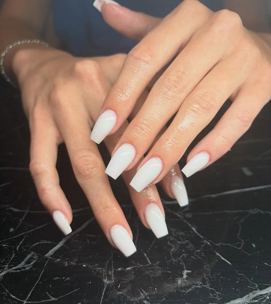 Long white coffin nails against black marble