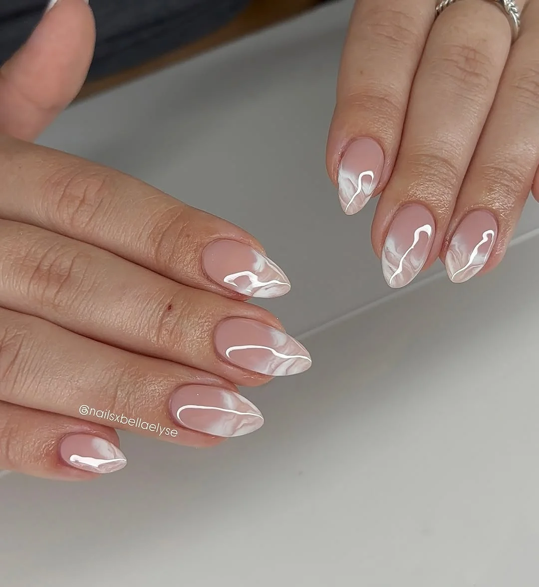 Nude almond nails with minimal white fine-line marble swirls