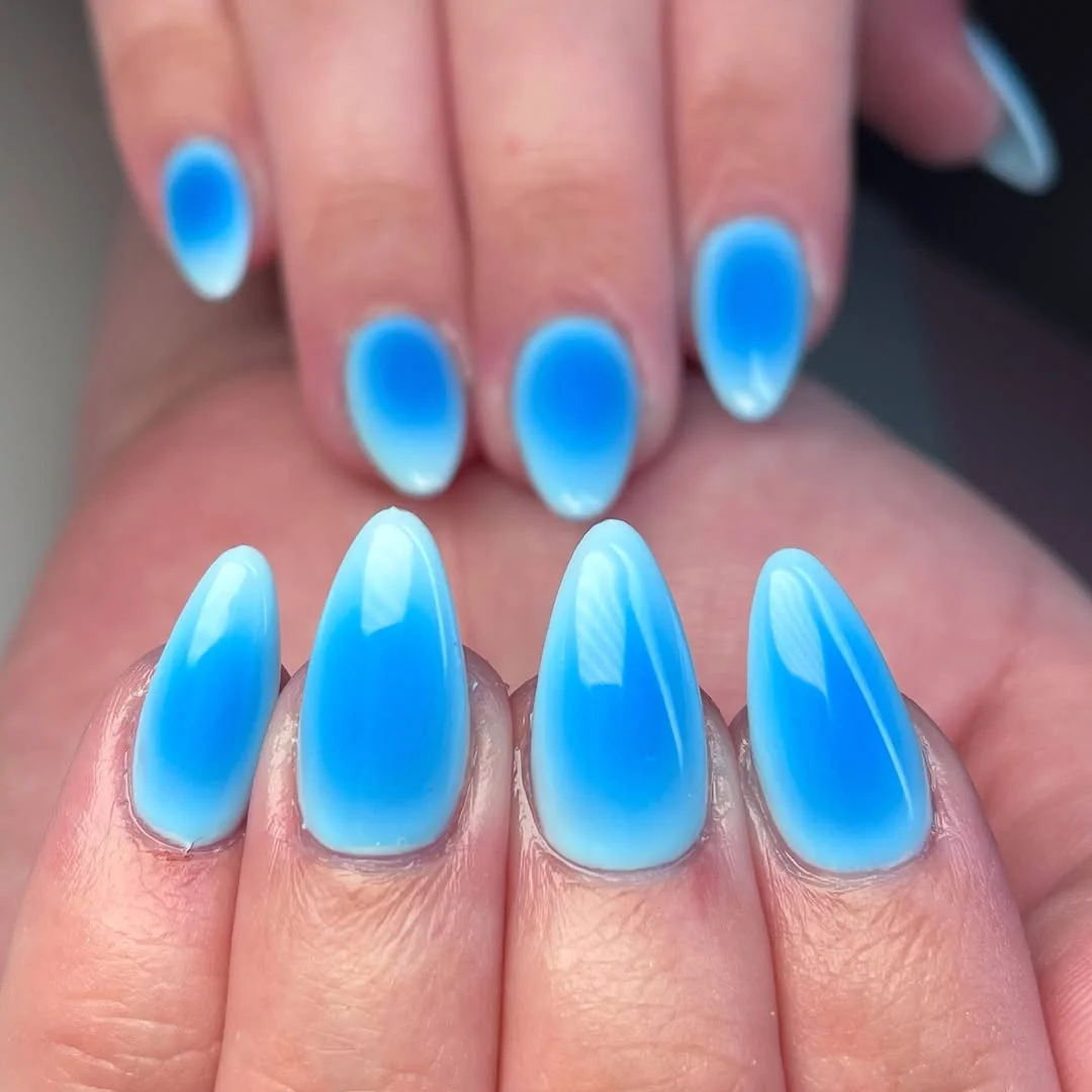 Bright blue aura almond nails in a poolside gradient