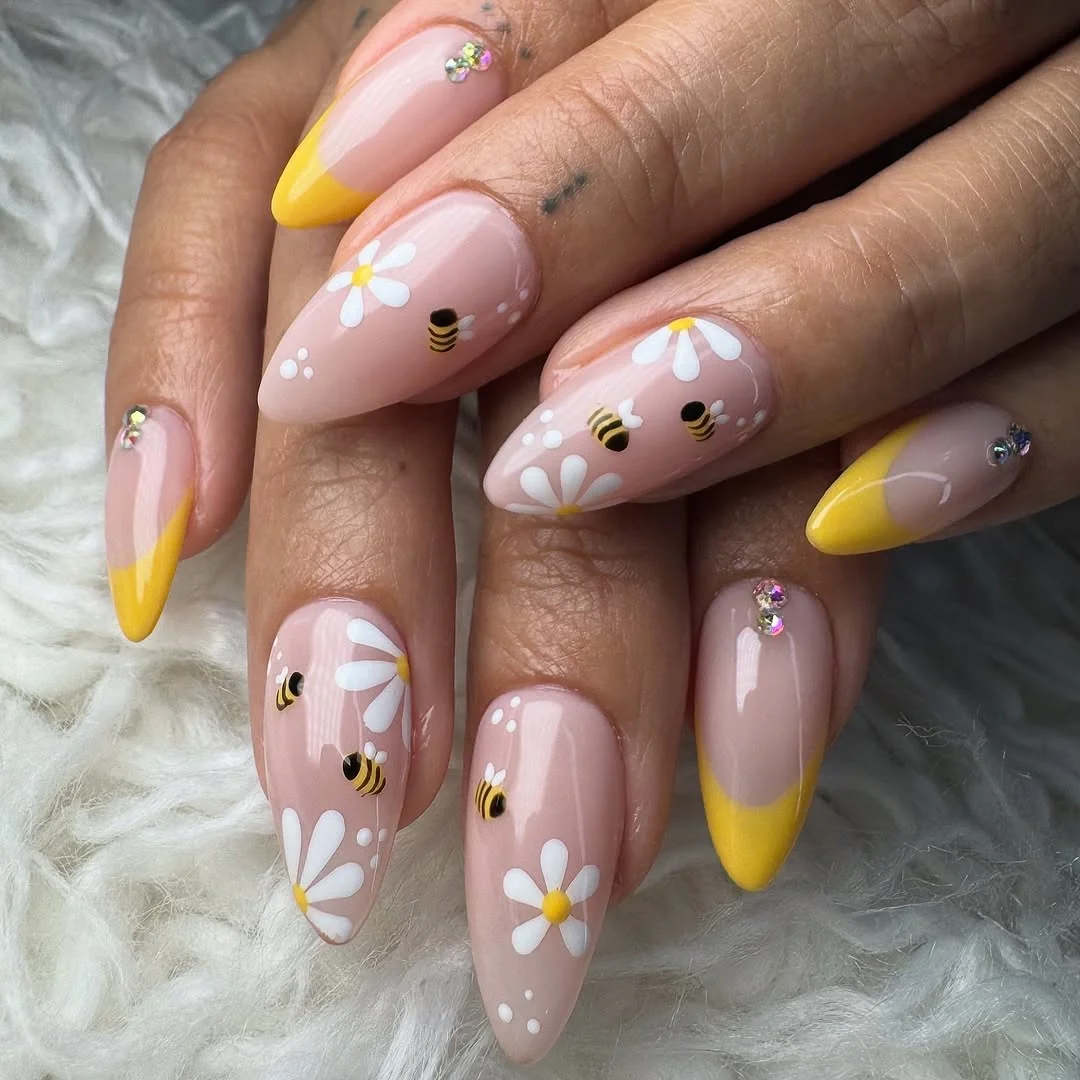 Nude almond nails with white daisies, bees and yellow French tips