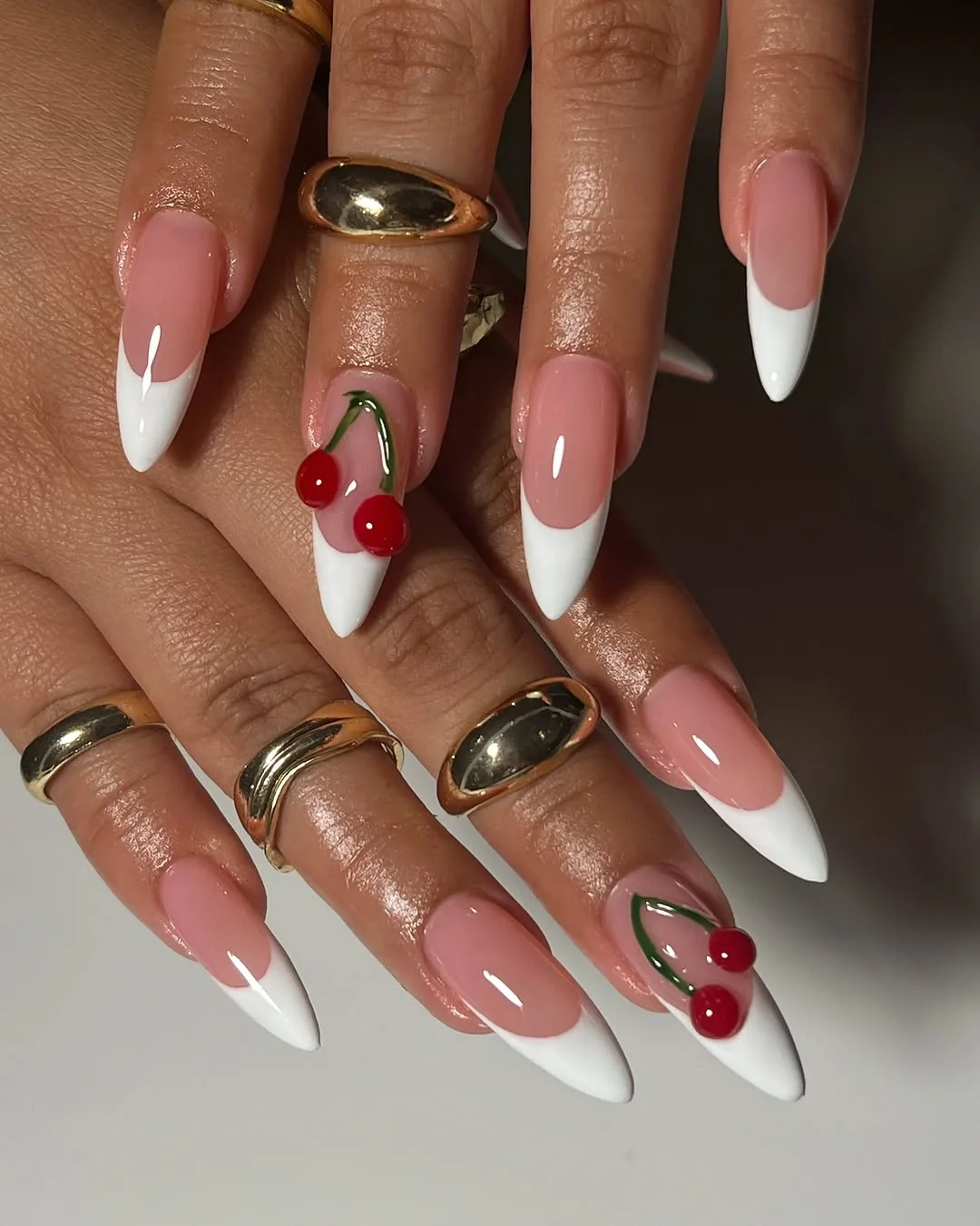 Almond nails with white French tips and a 3D cherry accent