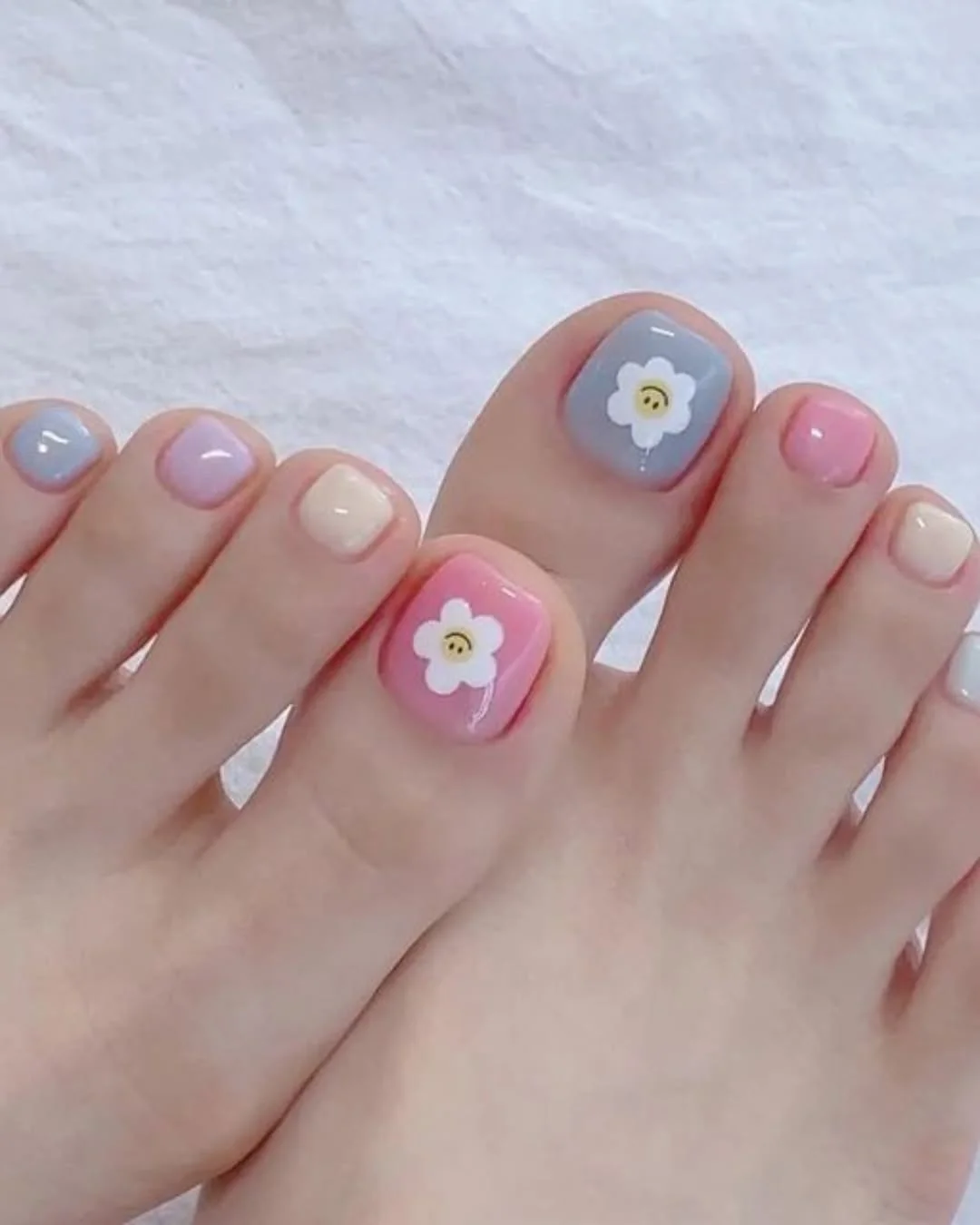 Pastel spring pedicure with a white daisy accent on the big toe