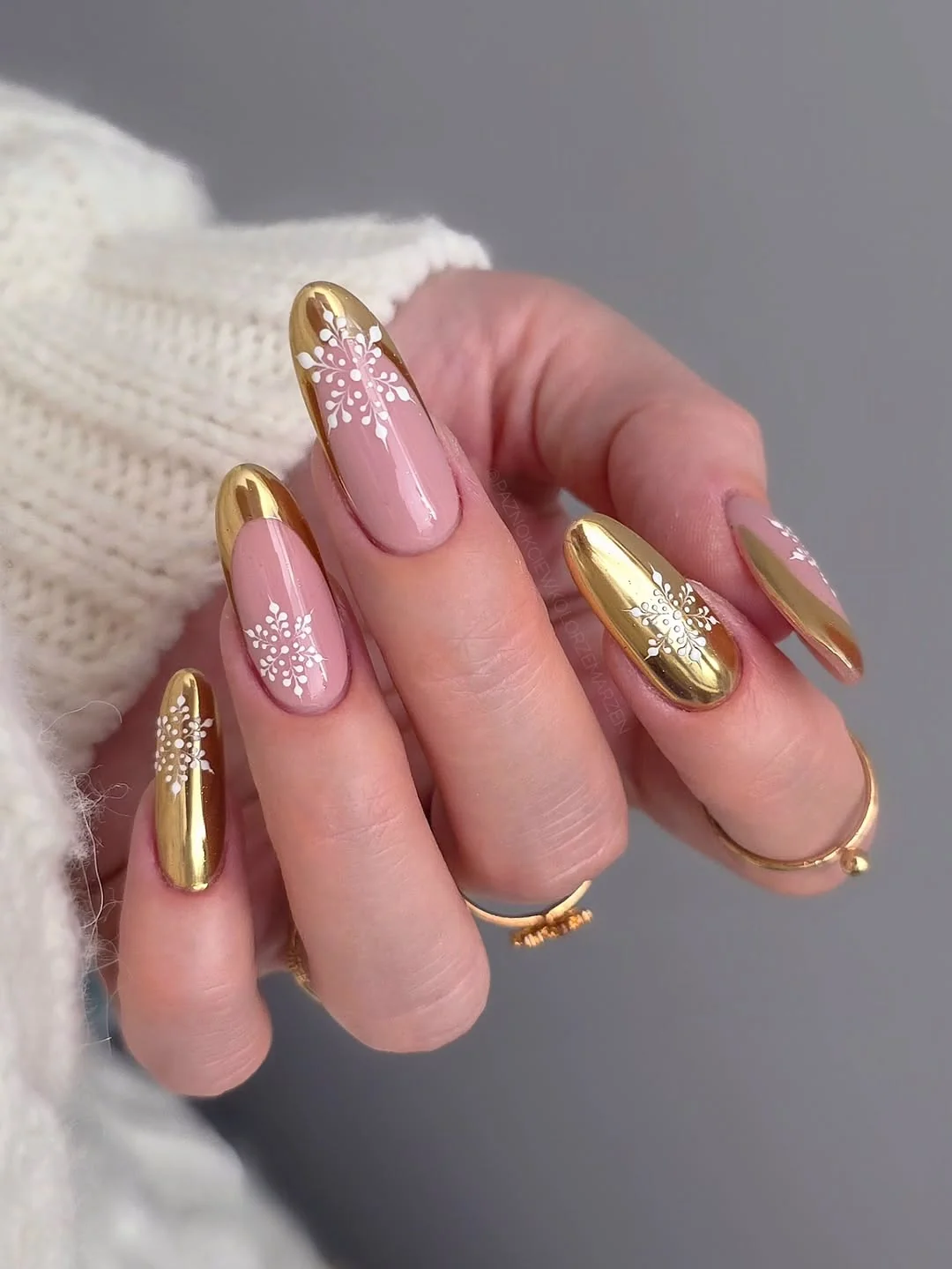 Nude almond nails with gold chrome accent nails and white snowflake glitter
