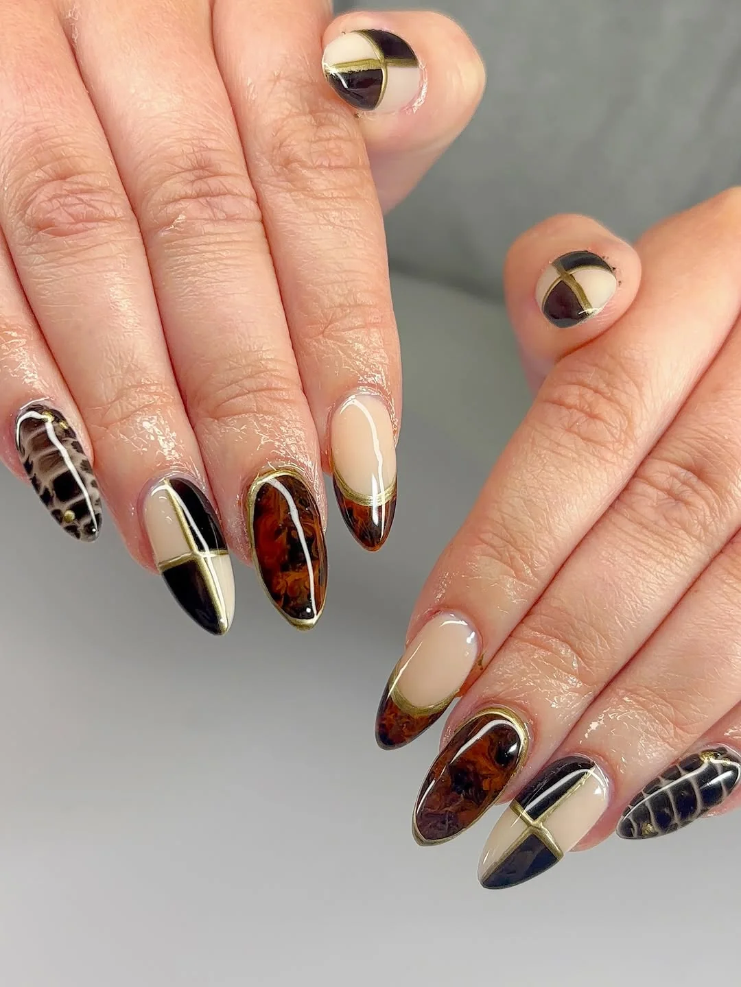 Black, cream and tortoiseshell almond nails with gold line color-block art