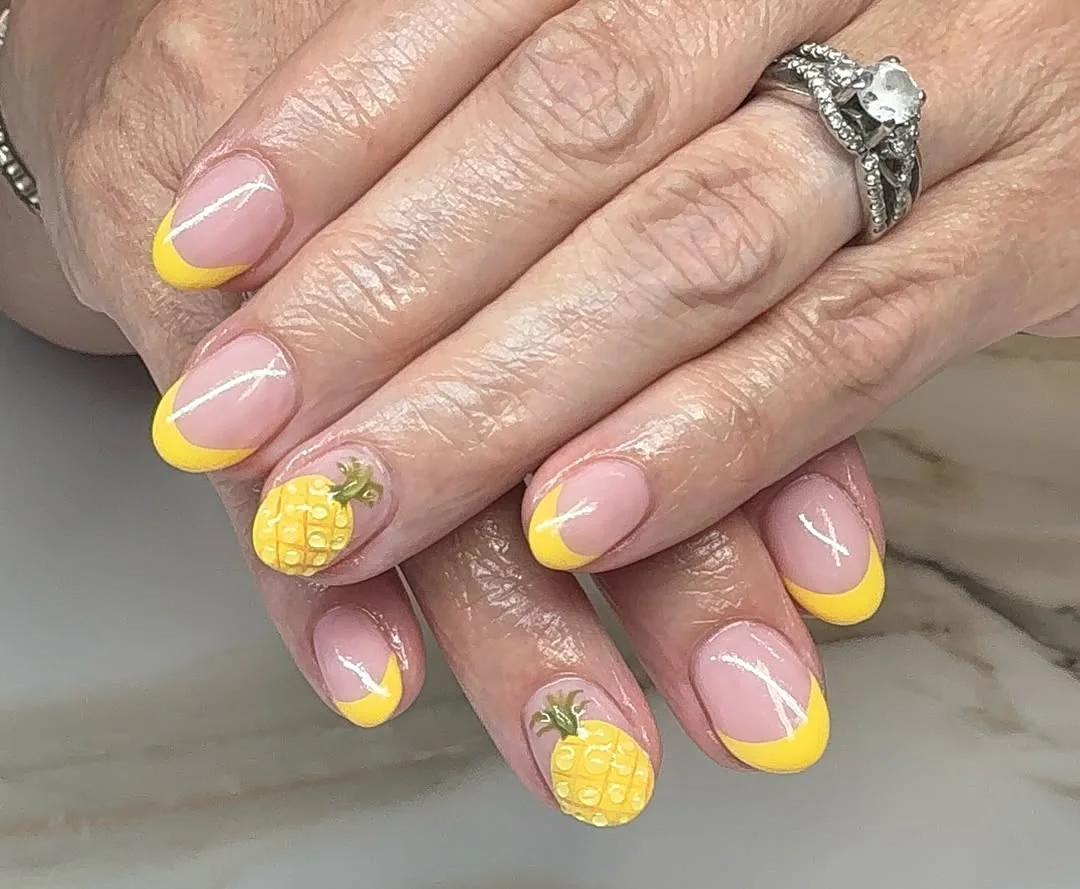 Short nude nails with yellow French tips and 3D pineapple accents
