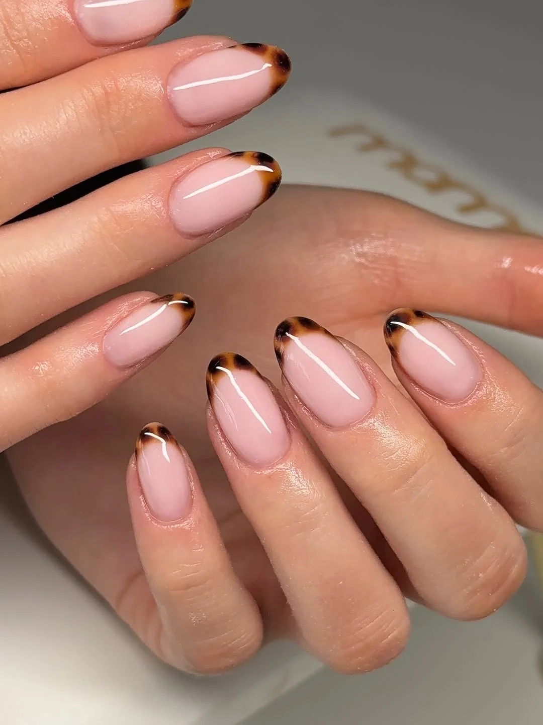 Sheer nude almond nails with micro tortoiseshell French tips