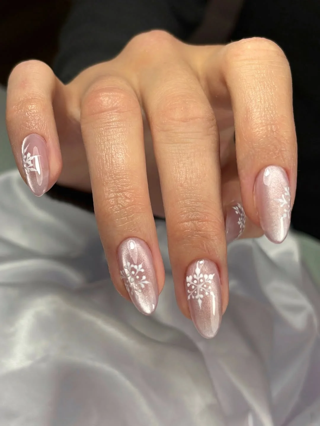Sheer pearly almond nails with snowflake and pearl accents