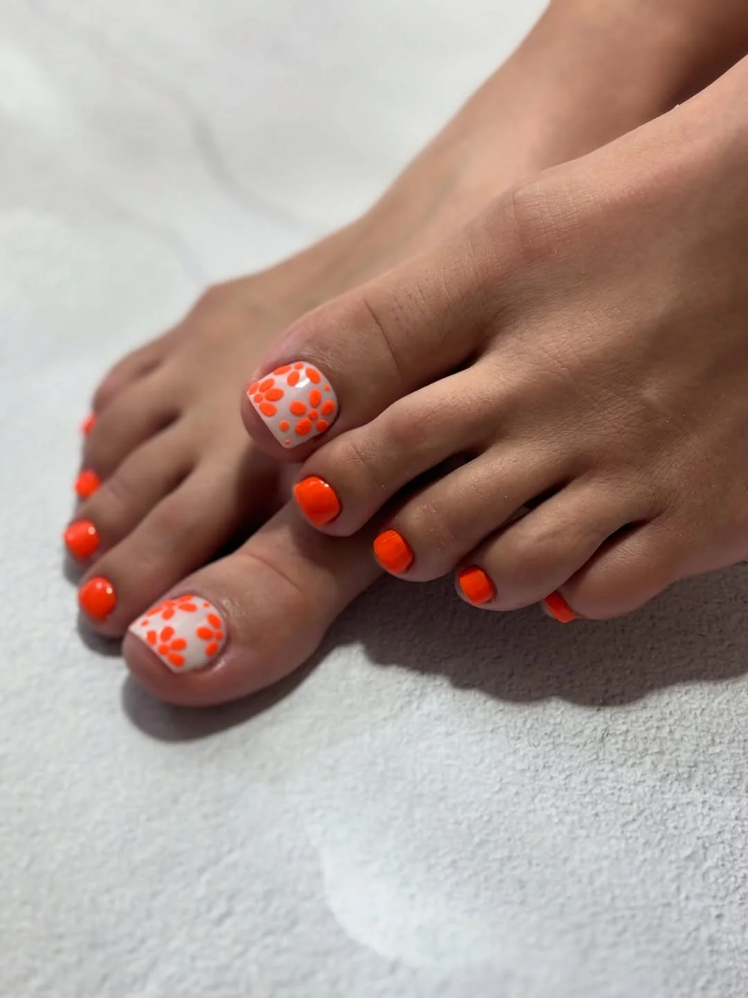 Summer pedicure with orange polka dot and orange toenails