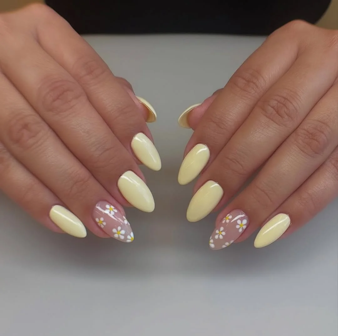 Pale yellow almond nails with daisy half-moon accent nails