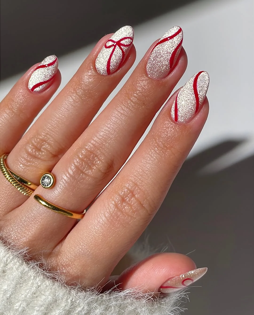 Almond nails with red candy cane stripes and ribbon bow accent art
