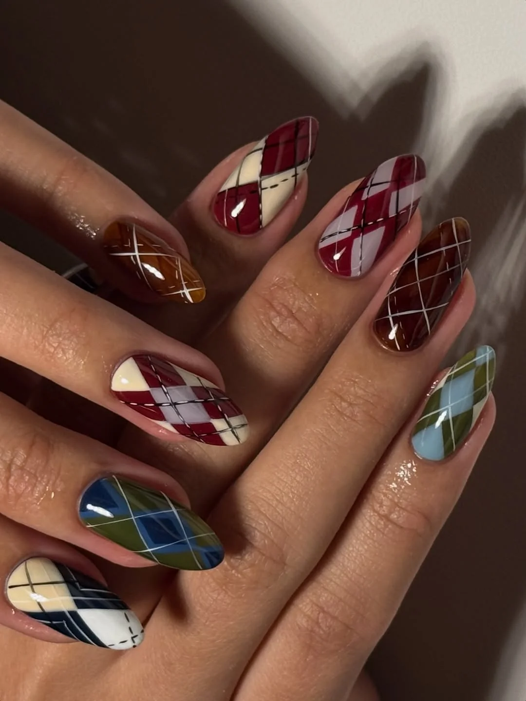 Almond nails with burgundy, cream and navy argyle sweater pattern