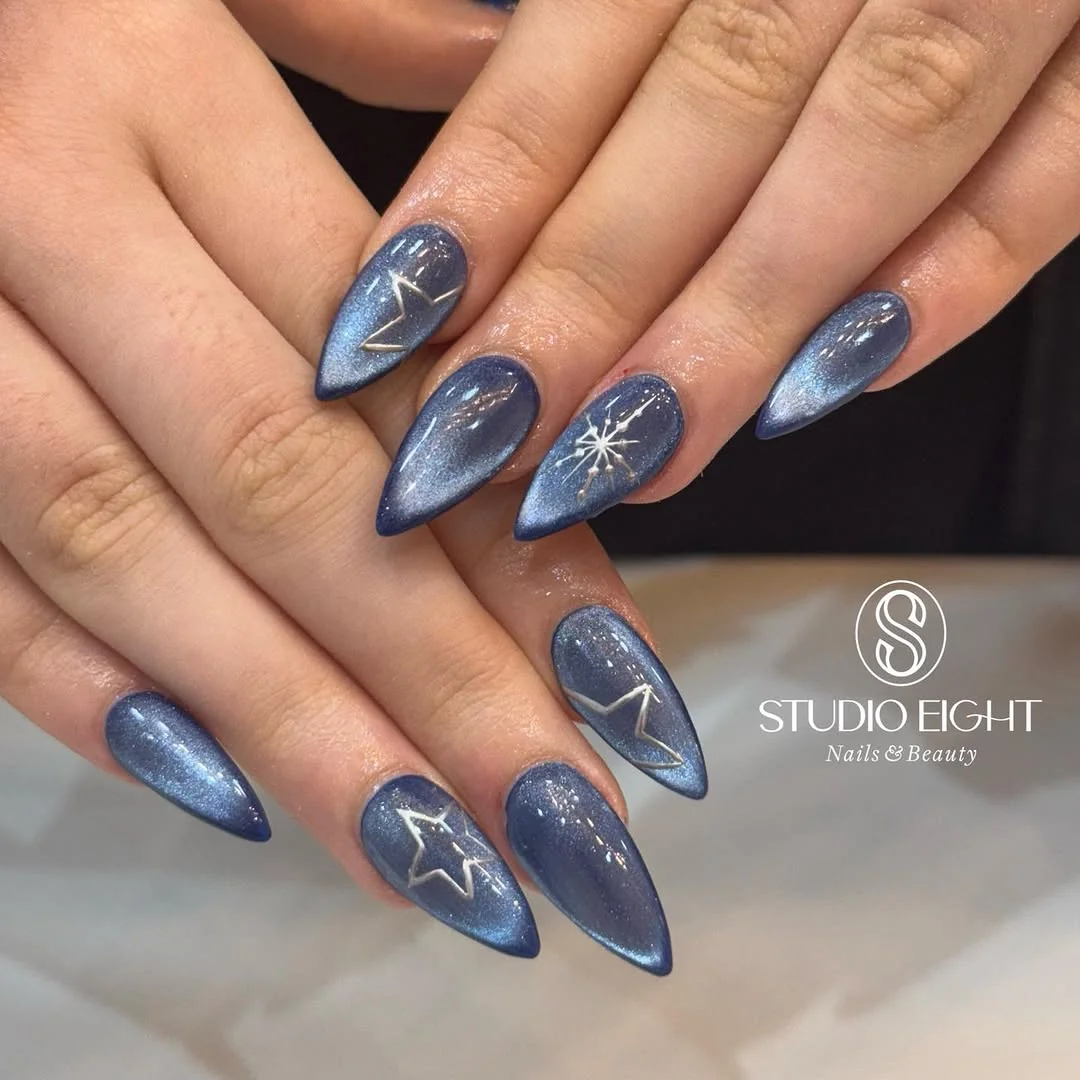 Blue cat-eye almond nails with silver snowflake and star outlines
