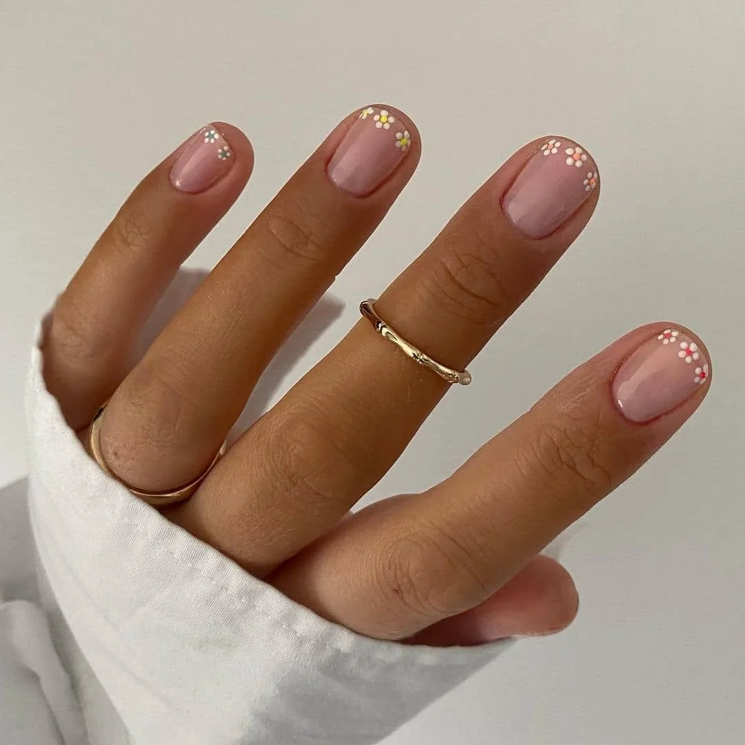 Short nude nails with tiny white daisy accents