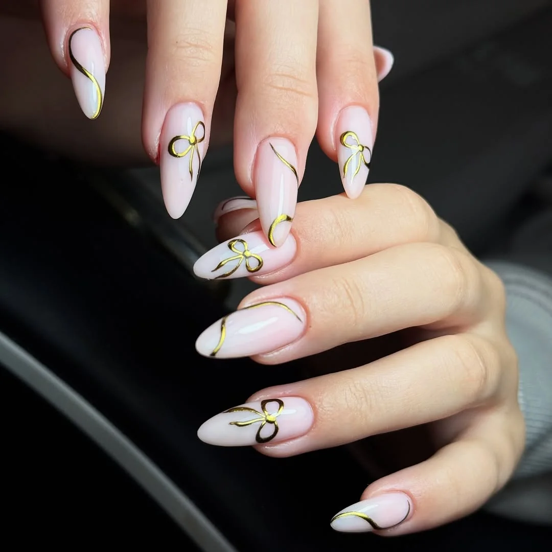 Light pink almond nails with chrome gold ribbon outlines