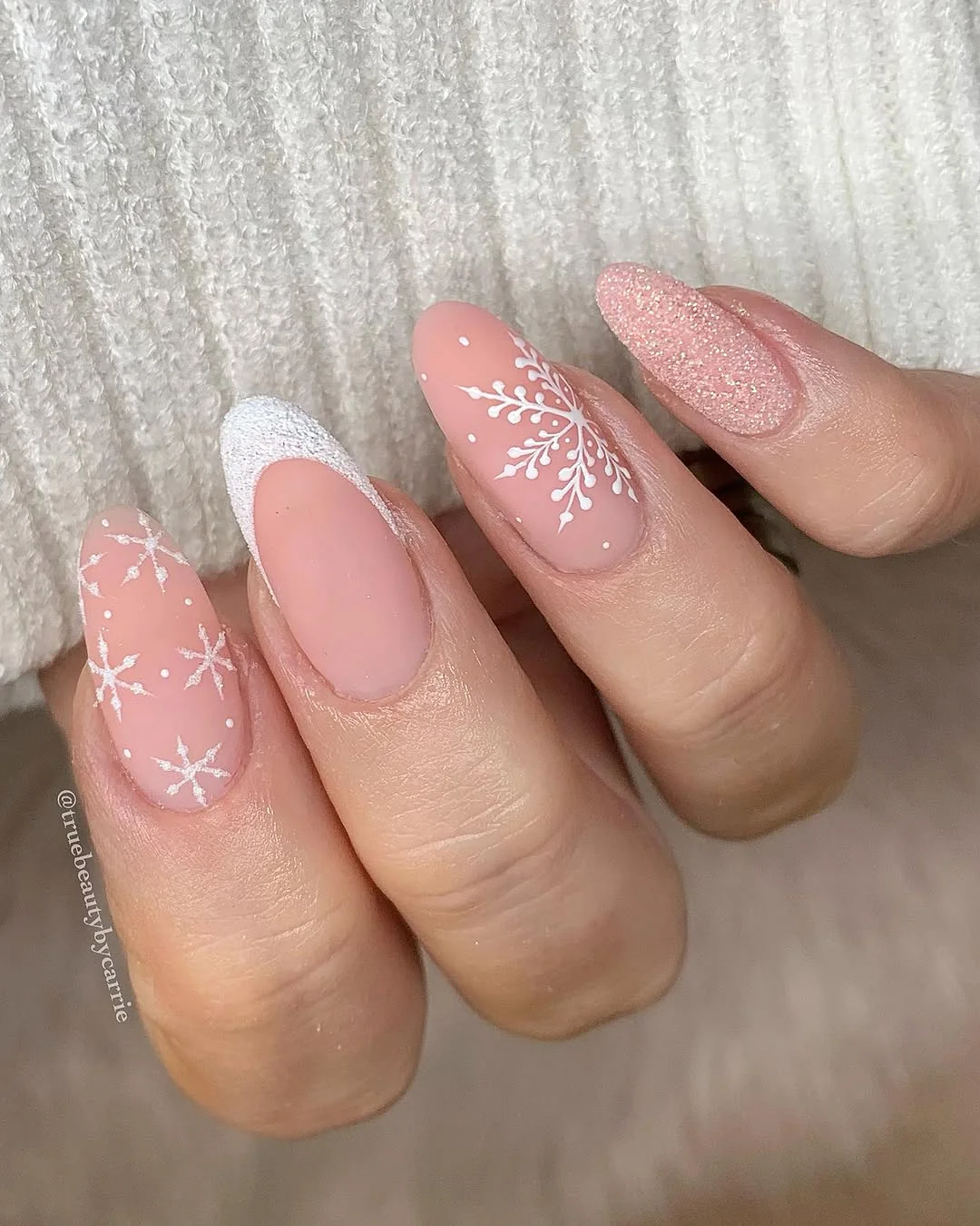 Nude almond nails with negative-space snowflakes and white French tip