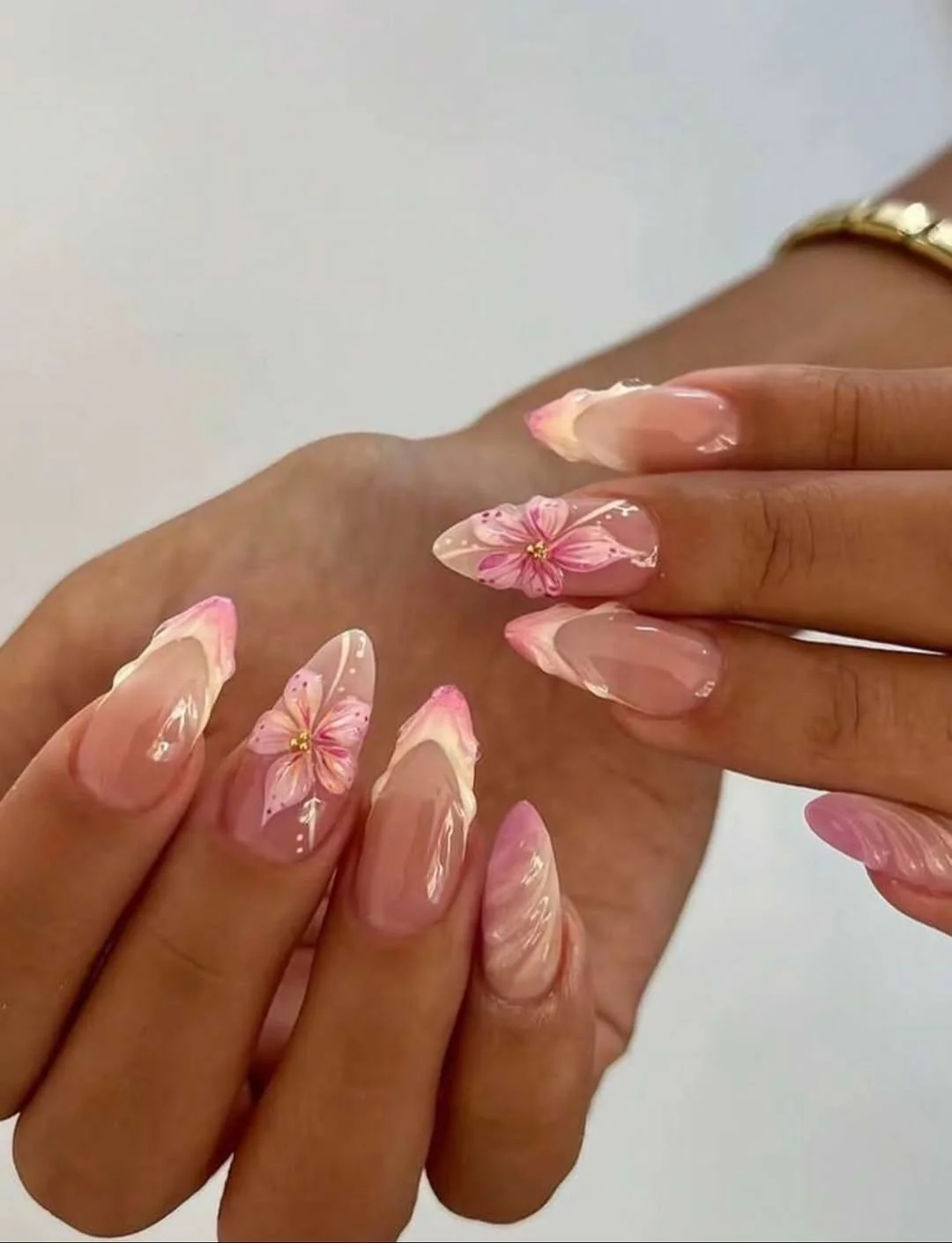 Sheer pink almond nails with hibiscus flower art and pink French tips