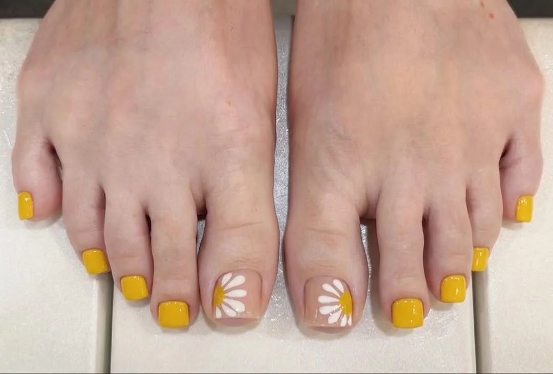 Yellow pedicure with white daisy art on the big toes