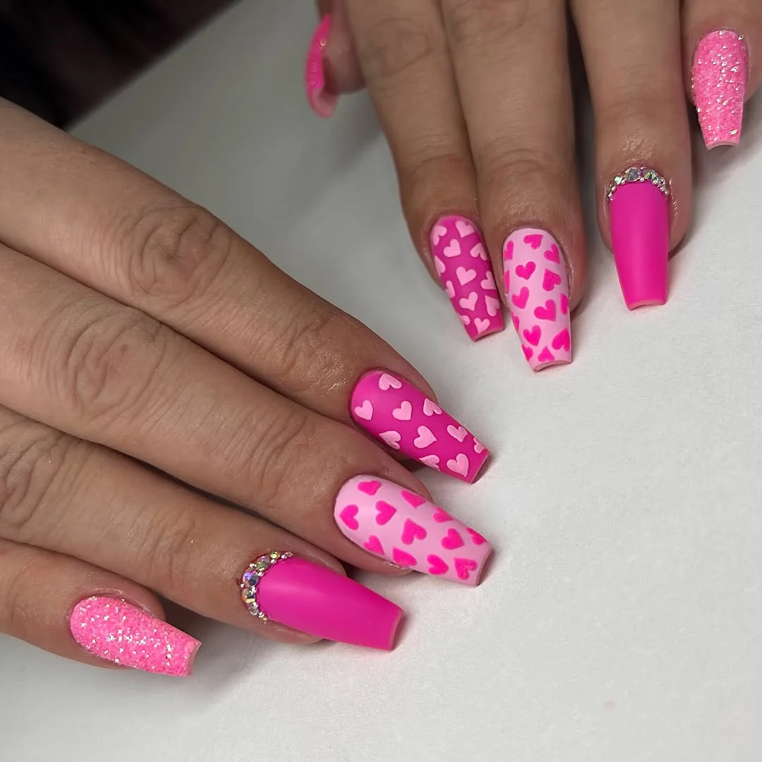 Hot pink coffin nails with heart pattern accents and glitter