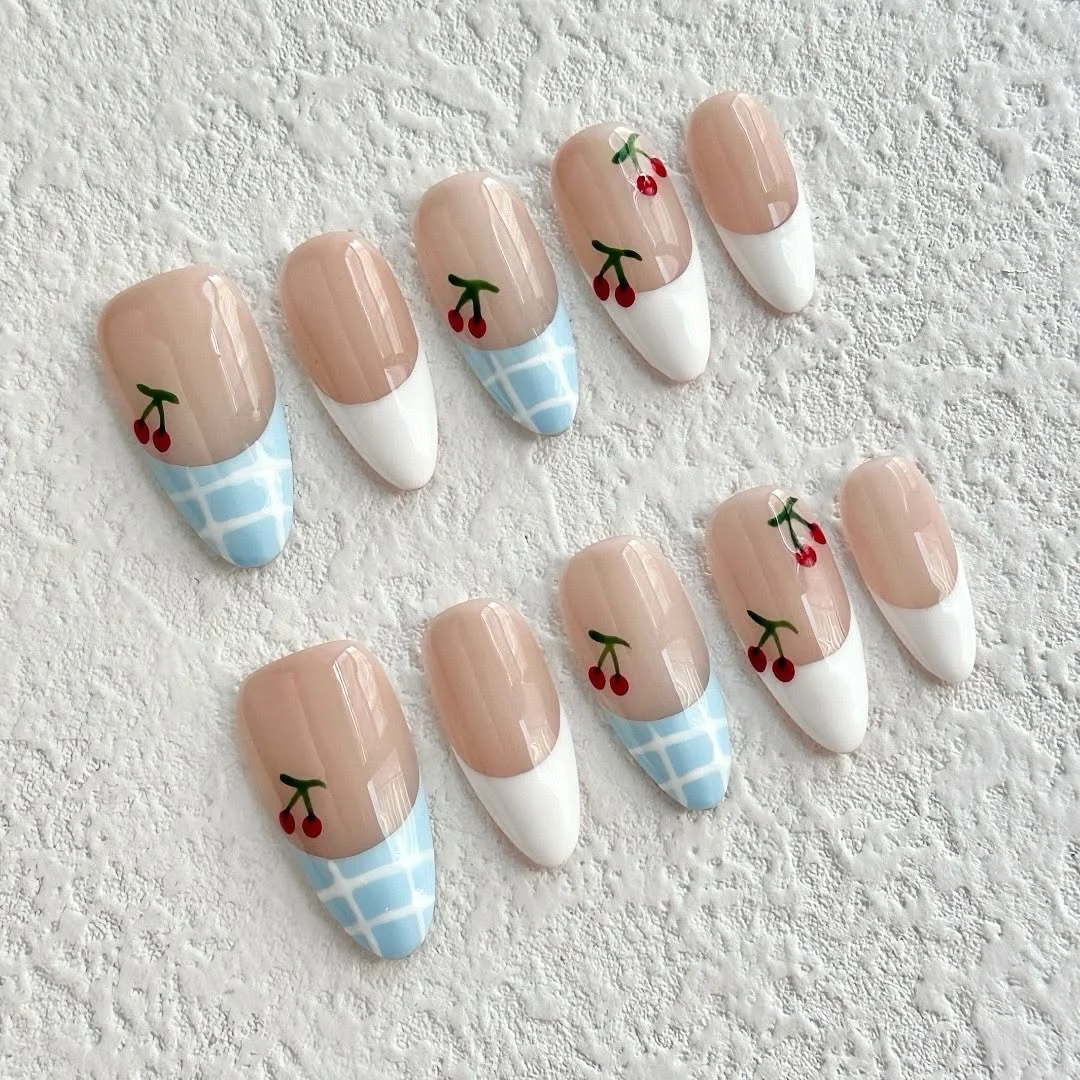 Press-on nails with white French tips, blue gingham and cherry details