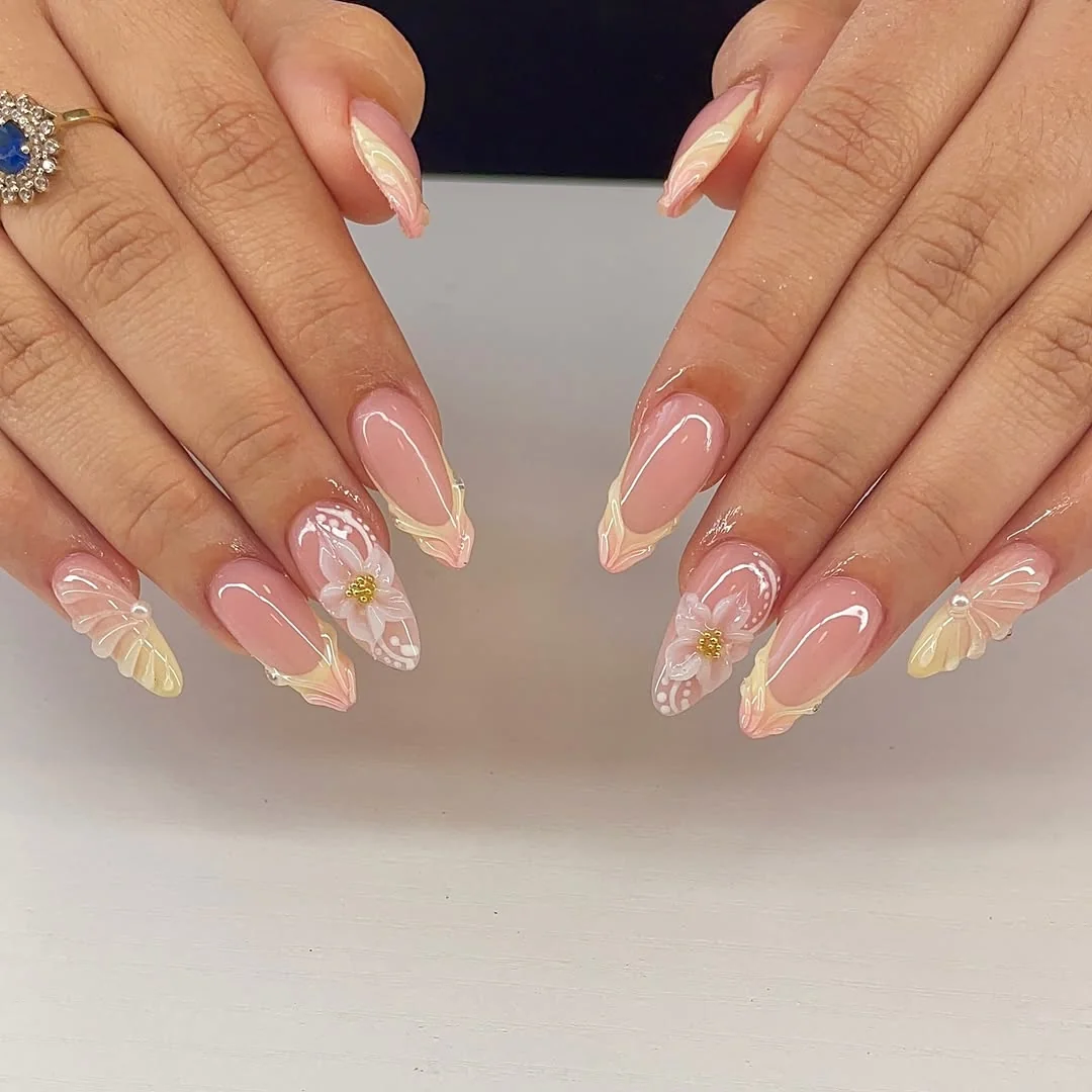 Almond nails with pastel French tips and flower accents on nude base