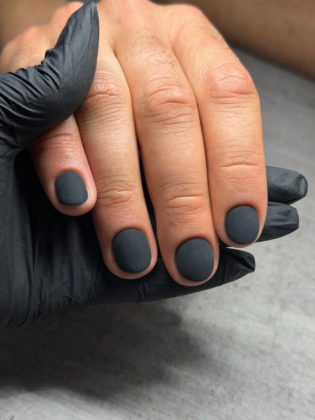 Short matte black nails on a masculine hand