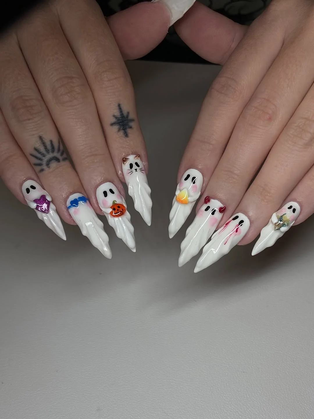 White stiletto nails with colorful tiny ghost and charm art
