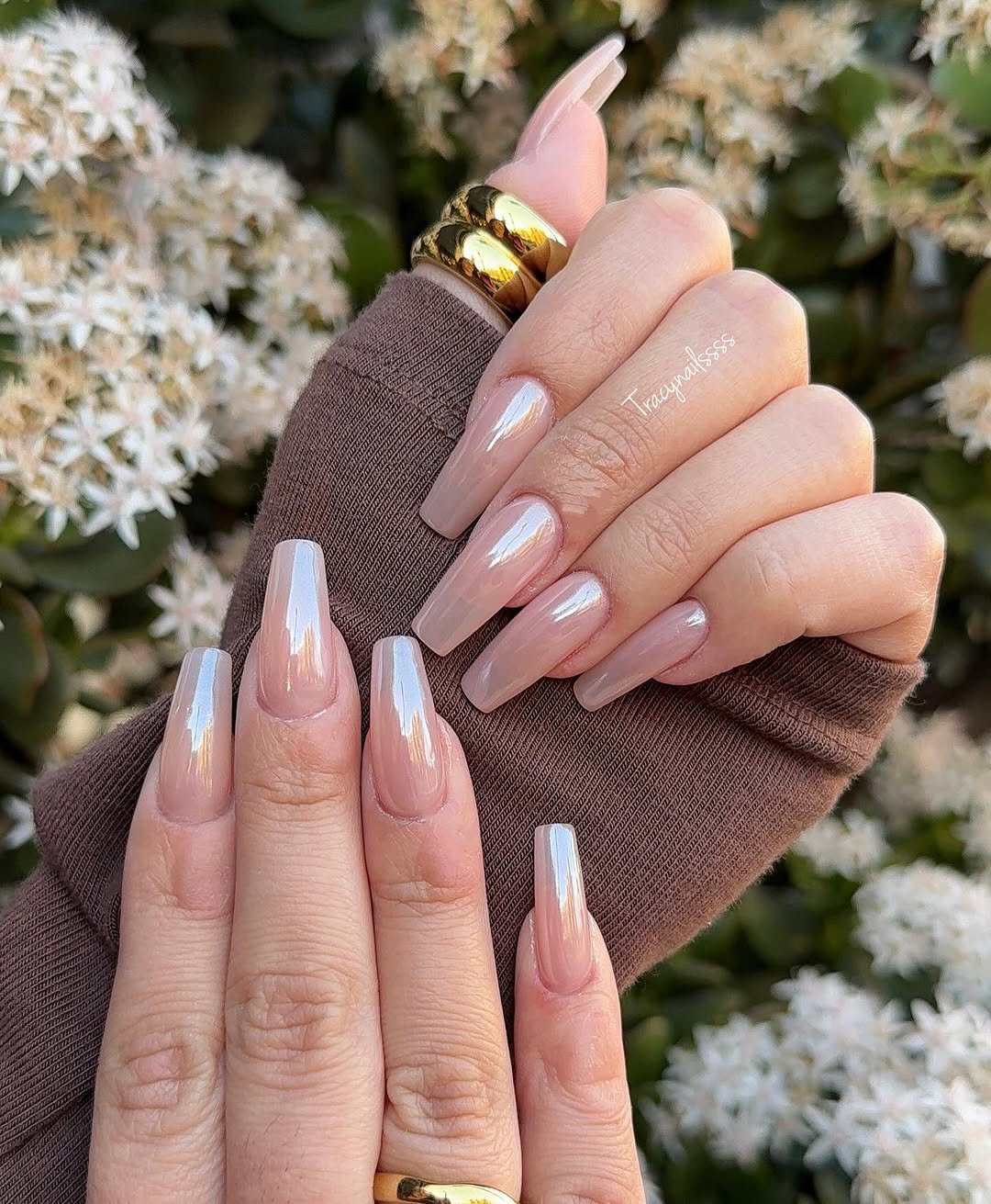 Long nails with pale milky French tips held in front of white spring flowers