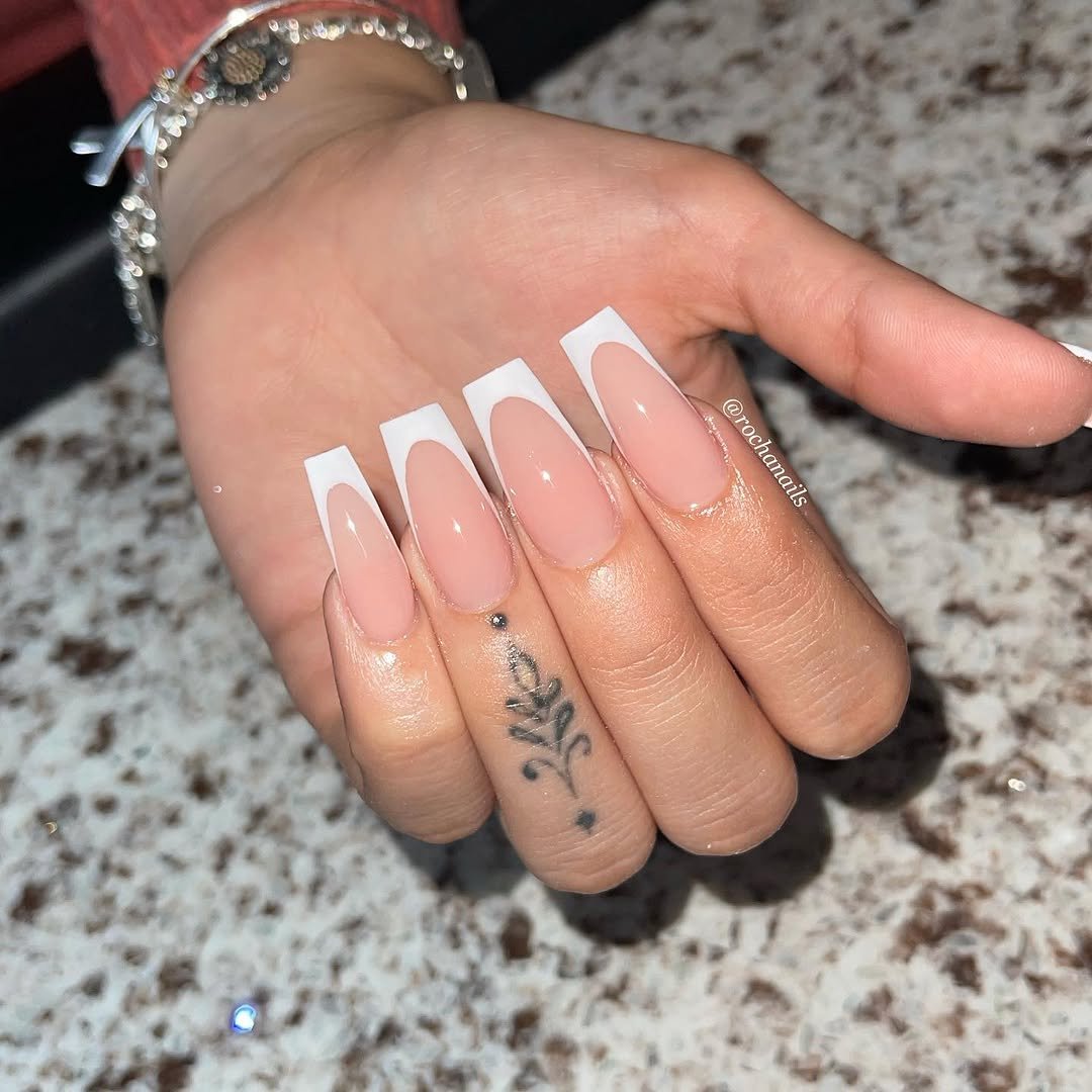 Long square nails with white French tips and a tiny sticker on the ring finger