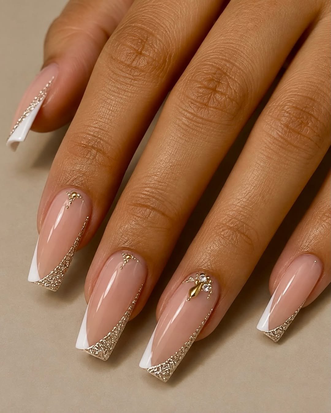 Coffin nails with a sheer nude base, white French tips and gold glitter edges