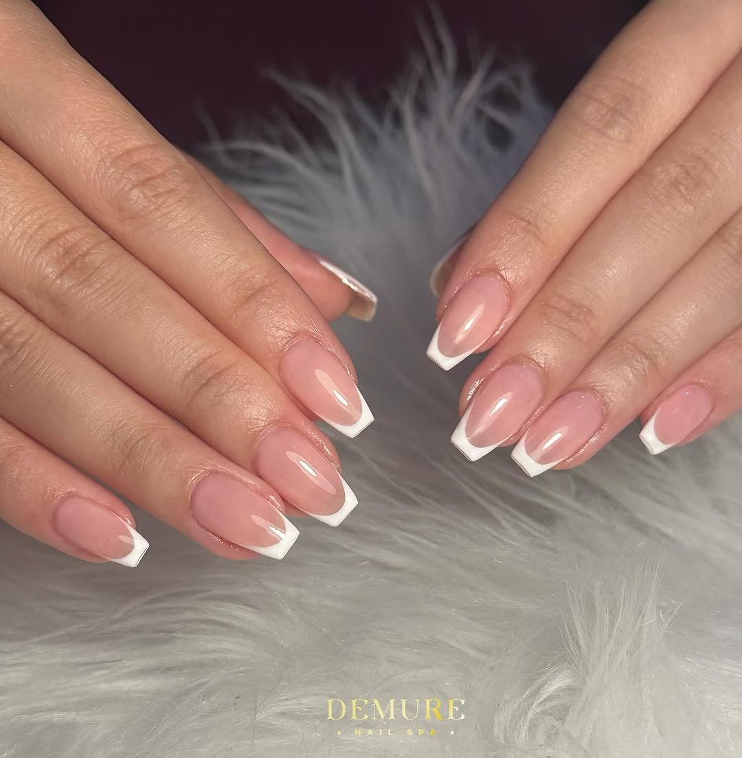 Almond nails with thin white French tips resting on white fluffy fur